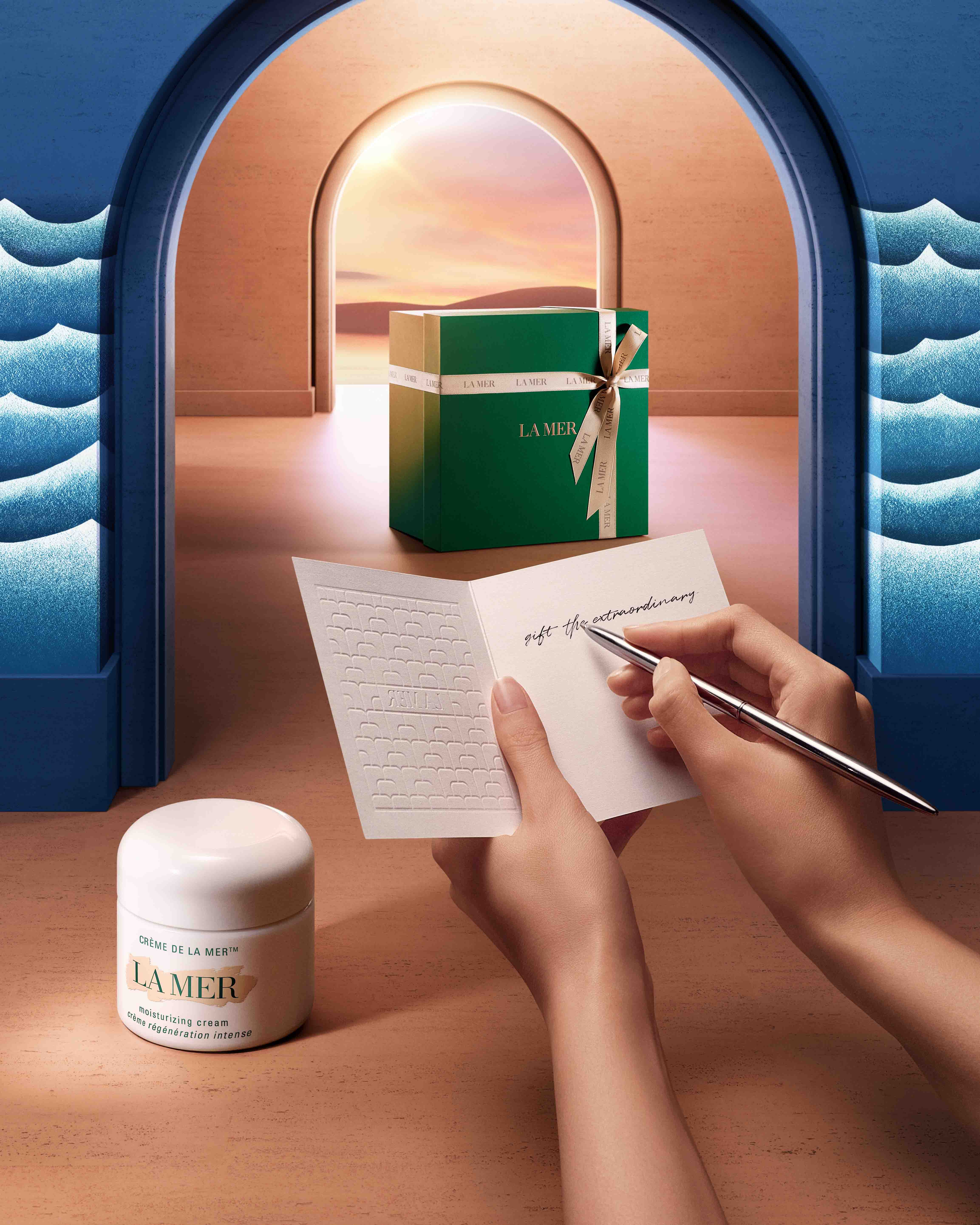 Photo of Creme de La Mer pot in the foreground with a hand writing a note and a la mer giftbox in the background against sunset.